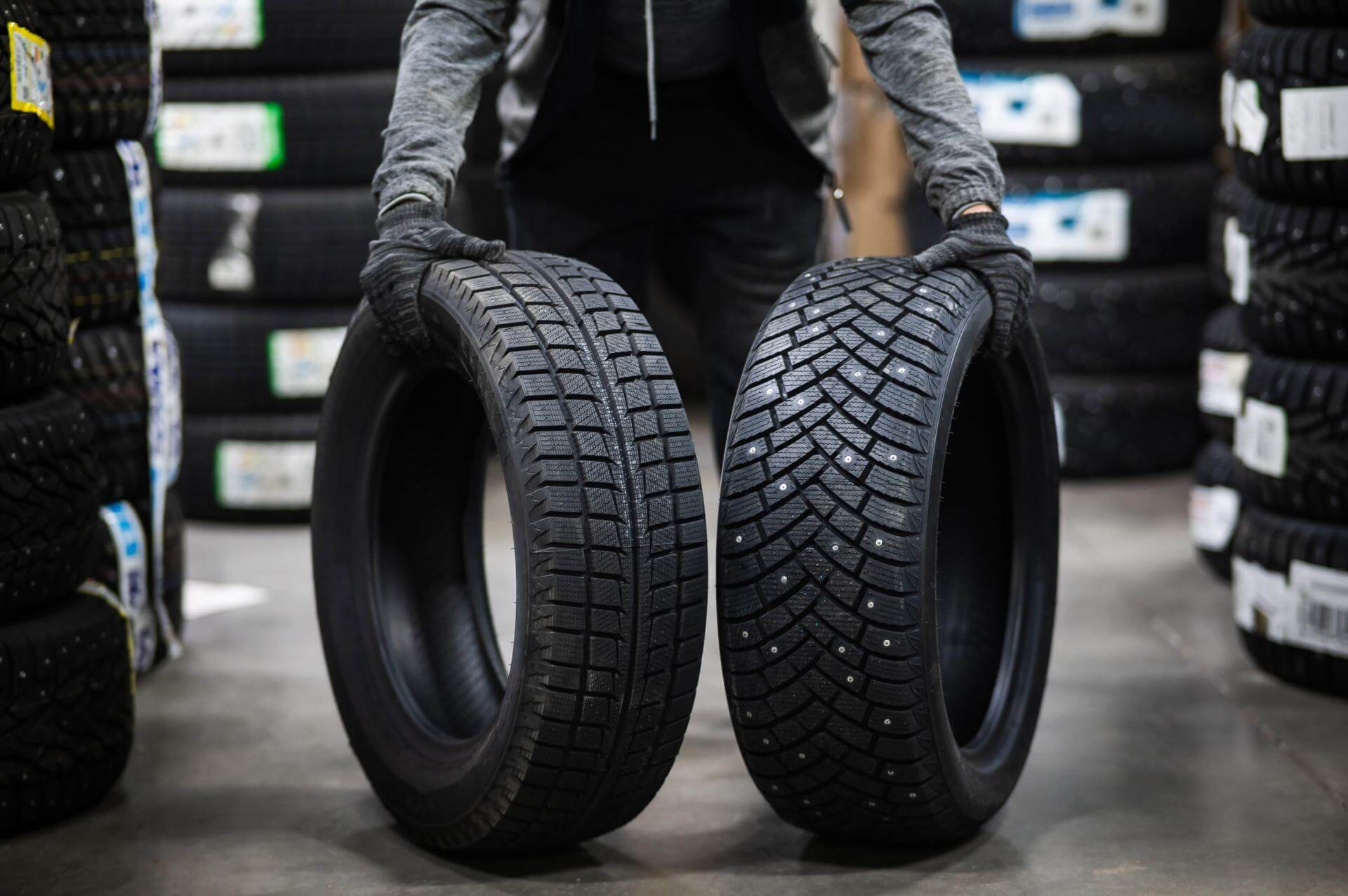 Meccanico mostra due tipi di gomme auto disposte in verticale